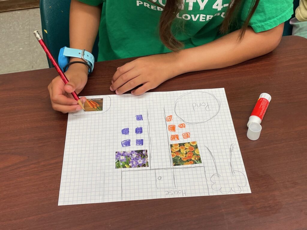 A young TOPS Camp attendee designs a colorful purple and orange garden with a pond and a carrot patch